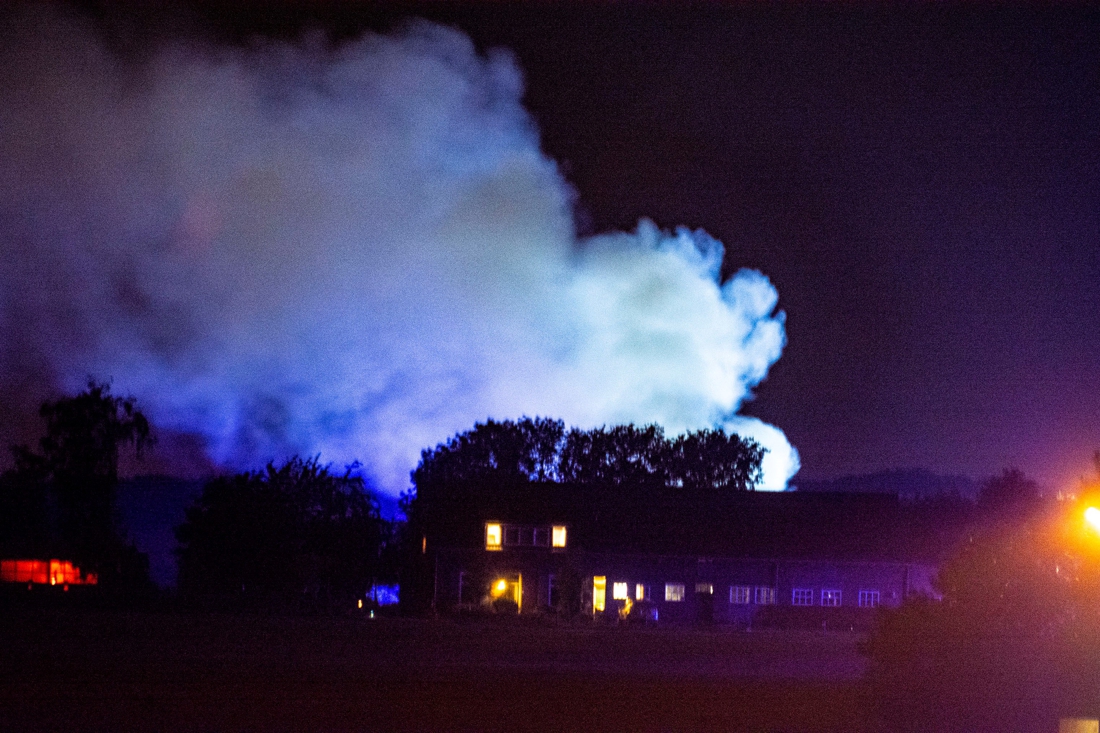 Uitslaande brand in loods met hooi, landbouwvoertuigen en dieseltank.
